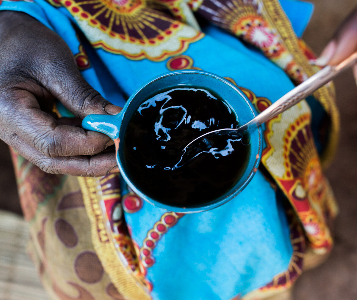 Burndian woman holding coffee cup and spoon