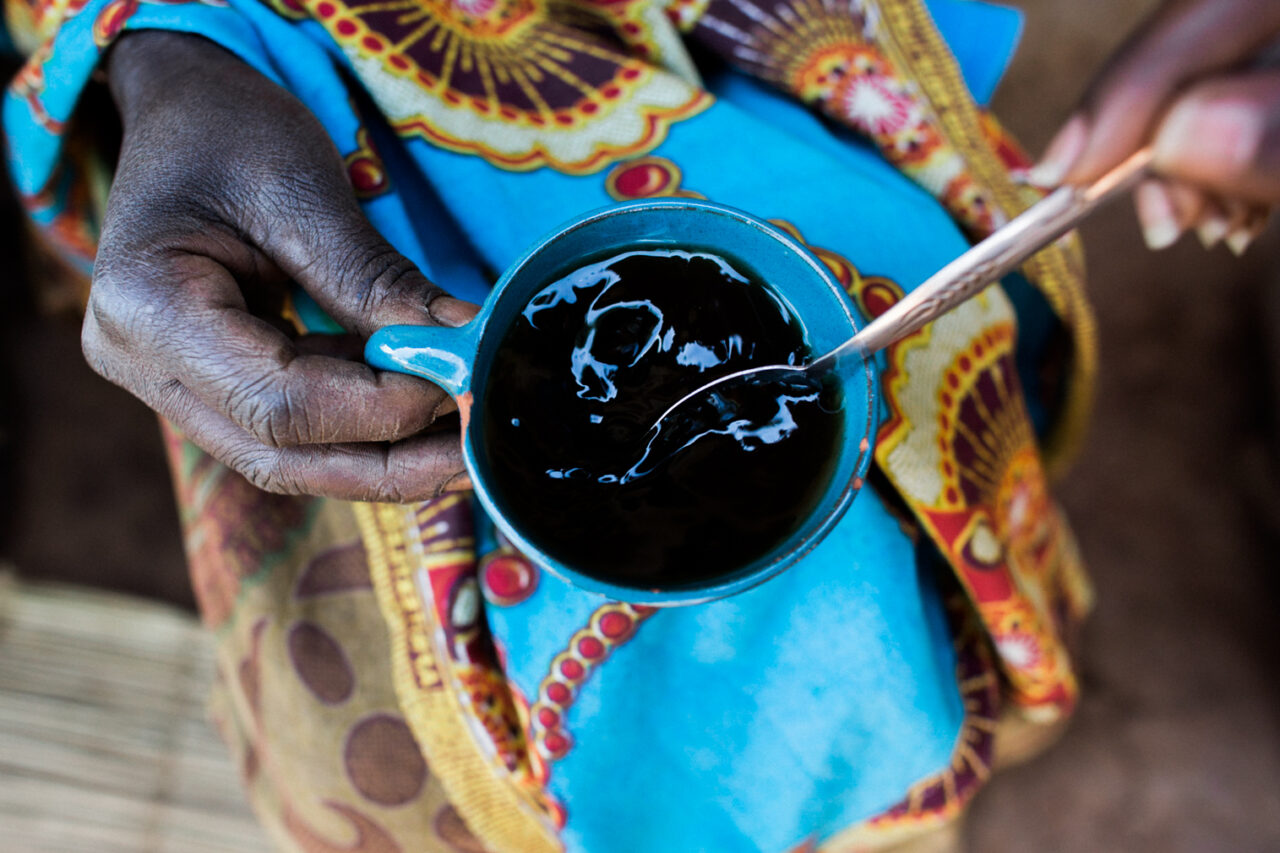 Burndian woman holding coffee cup and spoon