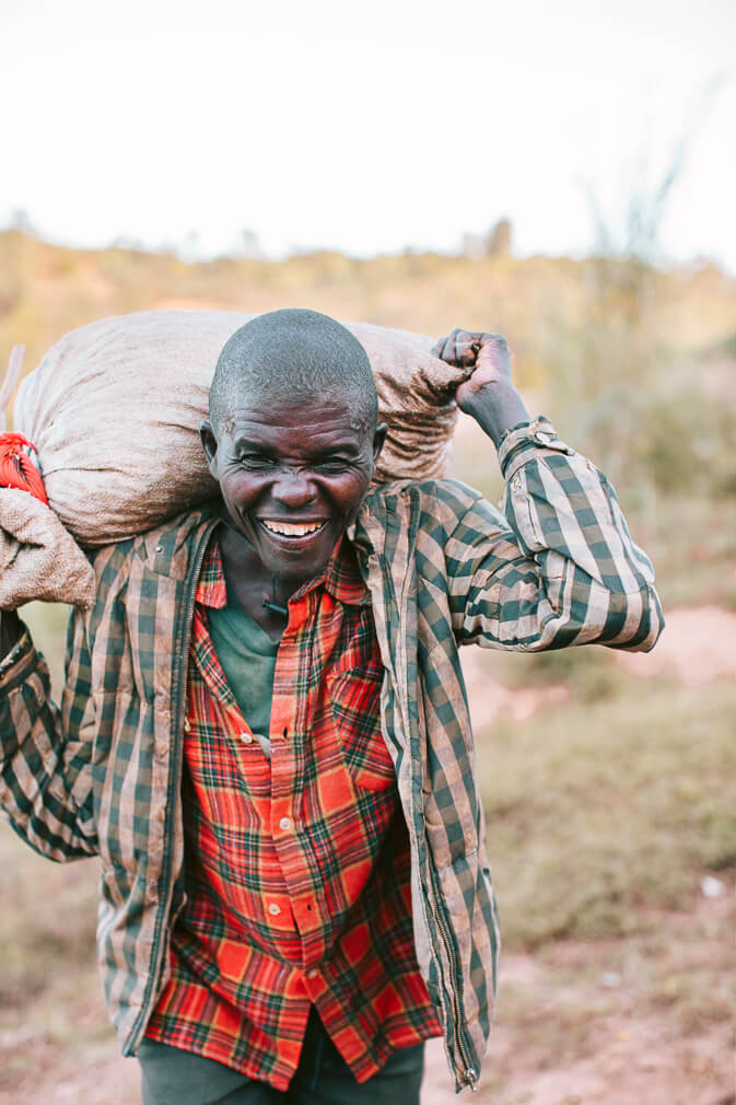 Burundian coffee farmer carrying a bag coffee cherries