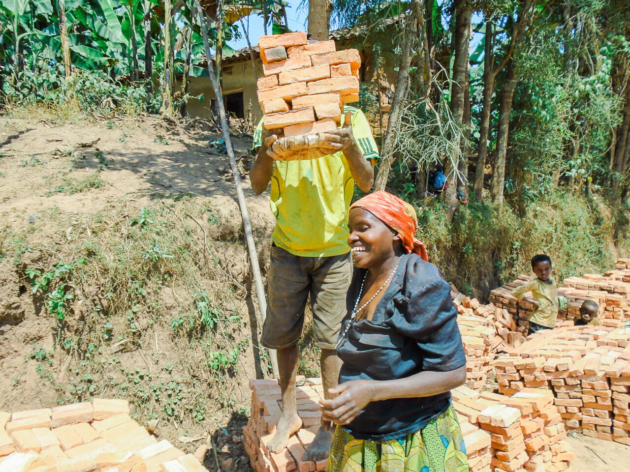 A Burundian man and woman carrying bricks