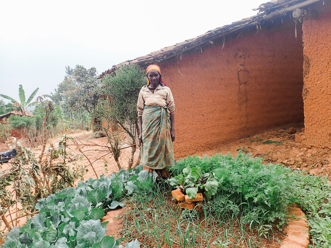 A Burundian woman standing by her kitchen garden