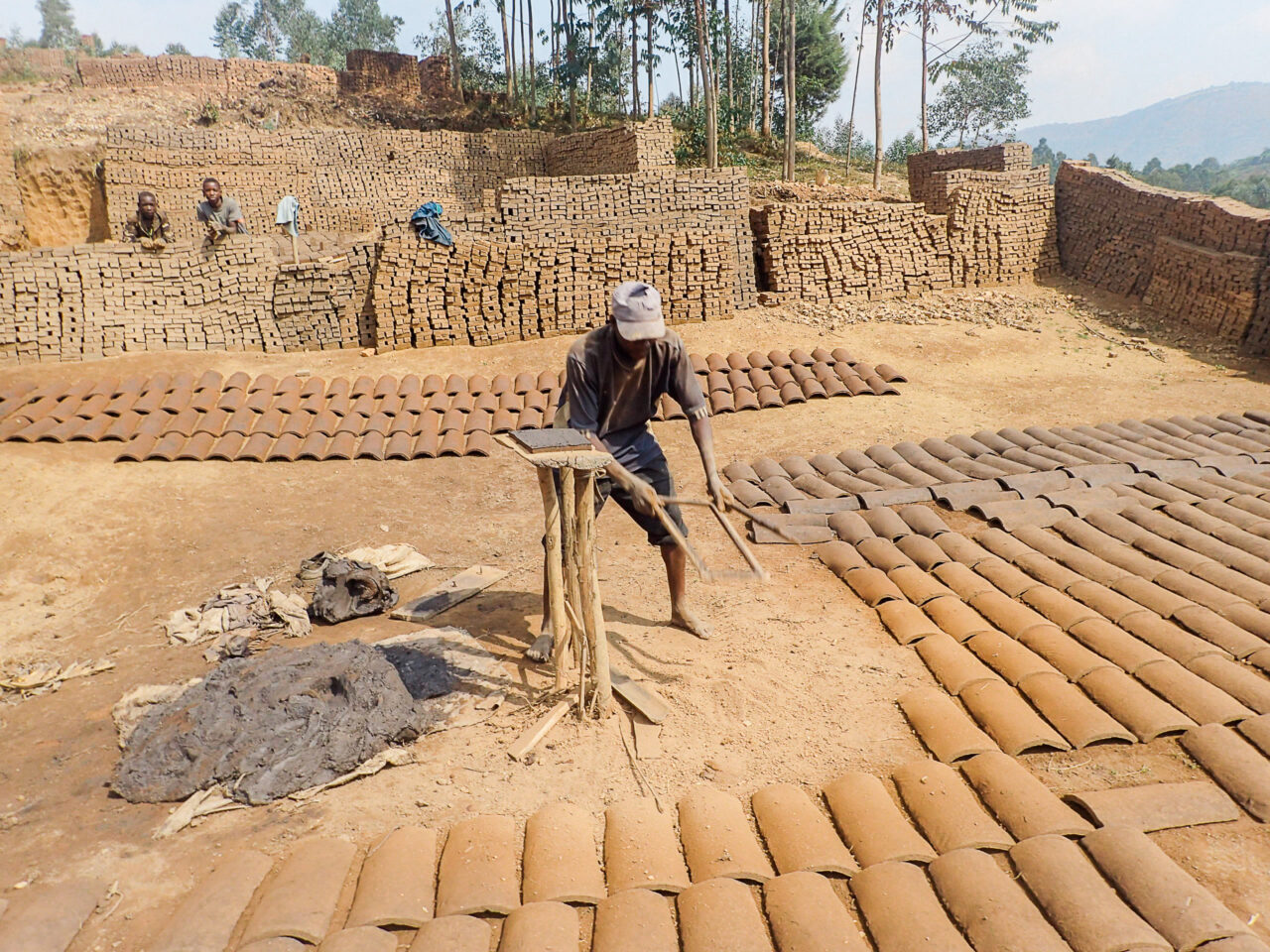 A Burundian man making clay roof tiles by hand